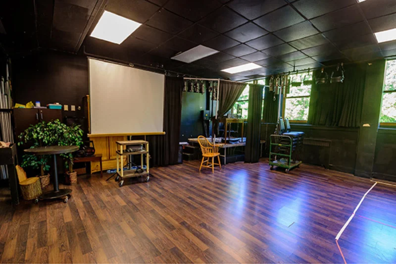 The rustic inside of the Marywood Black Box Theater with dark wooden floors, plants, and objects hanging from the walls
