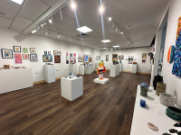 The Suraci Art Gallary with a sculpture in the middle and paintings on the wall on both sides