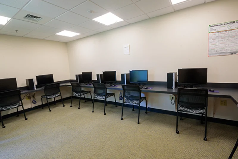 A computer lab with an L-shaped desk lining the wall