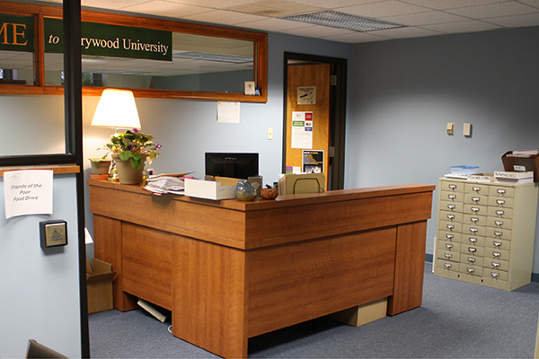 An L-shaped wooden desk with a filing cabinet inside the Human Resources office