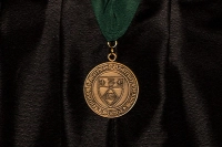 An academic medal on a ribbon is pictured in front of an academic robe