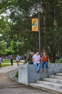two students sit on liberal arts steps near pacers flag pole