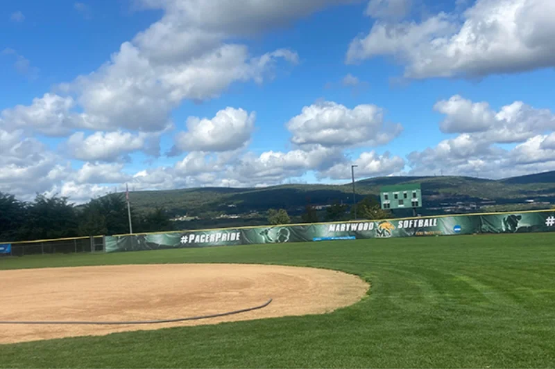 The Marywood softball field with a view of the mountains and a Marywood banner covering the fence