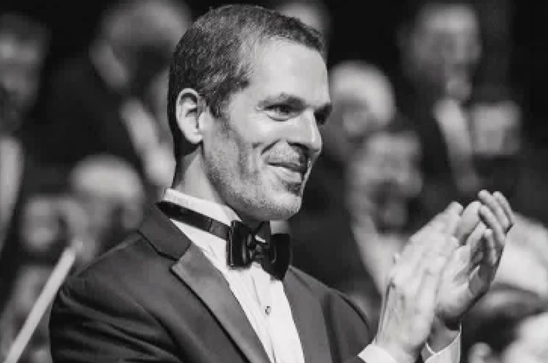 Black and white photo of a man in a tuxedo clapping Dr. Rick Hoffenberg Making Carnegie Hall Conducting Debut