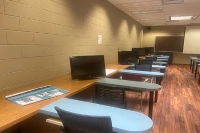 Blue desks with computers and a long wooden desk to the left