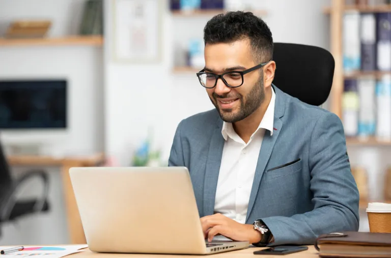 male student with glassed in grey suit on laptop