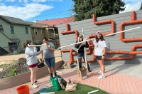 Students are shown finalizing the installation of a hydroponic pipe system for a community garden.