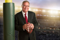 A man holding a football near a goal post