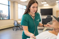 Female nursing student practices the use of a  stethoscope RN to BSN Fastest Program: Accelerate Your Nursing Career with Excellence