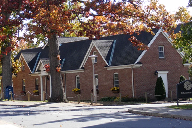 Red and yellow leaved trees stand in front of the Marywood mailing and printing center