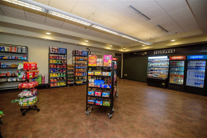 Fridges with drinks cover the walls along with displays of cereal and other snacks