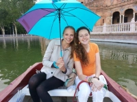 two female students in Sevilla with umbrella on boat