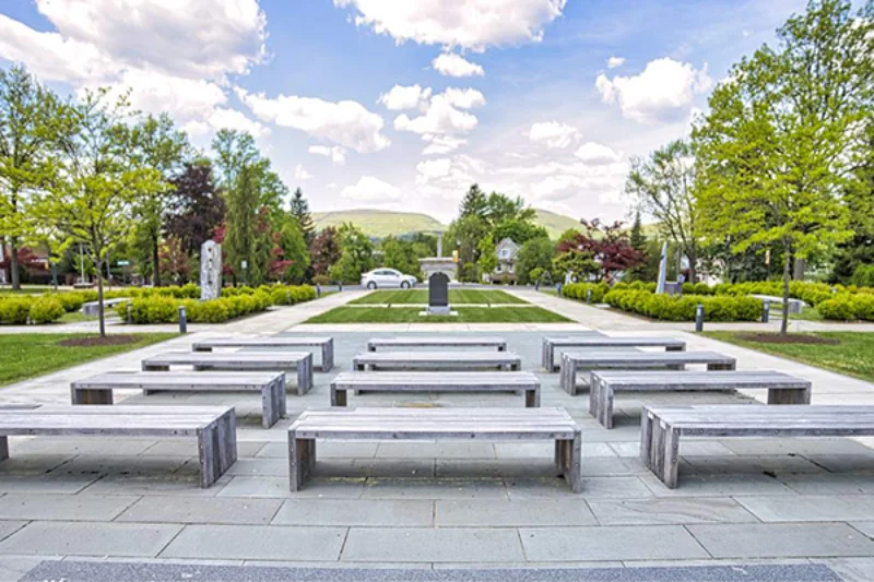 Four rows of three benches sit upon the tiled groun in the Marywood memorial gardens