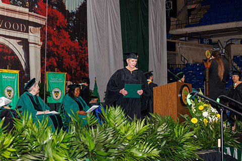 Mary Howard carrying her diploma across the stage during graduation.