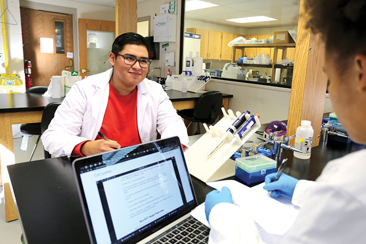 Two science students assist each other in a lab