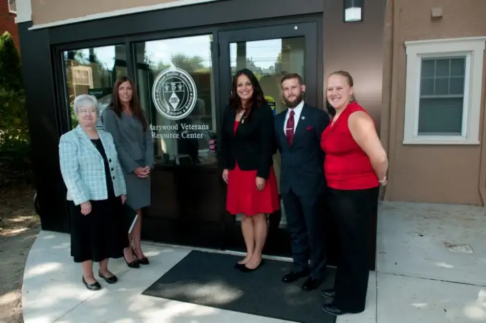 An image taken outside the Veterans Resource Center. There are several people standing outside the office looking into the camera.