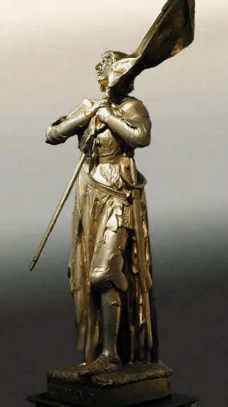 A sculpture of a man made of bronze holding a weapon of some sort over his left shoulder and looking off into the distance