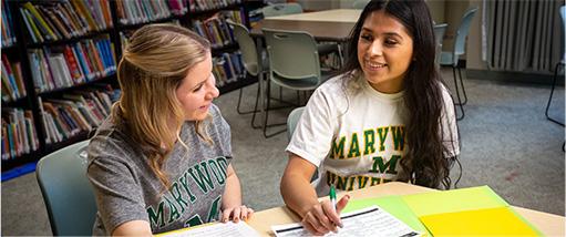 two female students sitting at table talking
