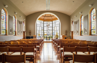 A view from the back of the Marian Chapel, displaying chairs and stained glass windows and doors