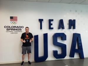 Nick Macano pictured next to a Team USA sign. Exercise Science Student Attends Team USA Symposium
