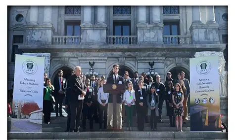 Austen Miller (center) makes a speech on the PA State Capitol Steps in support of funding for state grants.