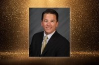 A formal headshot of a man in a suit against a gold glitter background Kelleher Selected to Serve as Judge for Miss America Pageant
