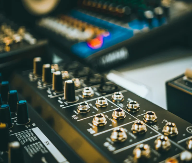Macro shot of professional audio equipment with faders knobs and buttons.