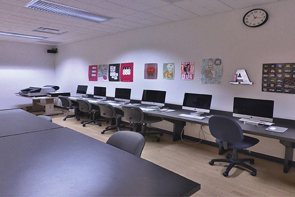 A visual arts classroom with computers and paintings on the wall