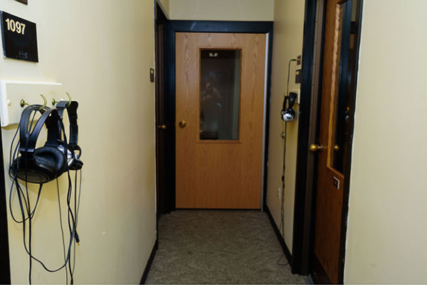 Headphones hang from both sides of the wall with a wooden door at the end of a hallway