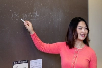 A music therapy professor holding a piece of chalk and standing at the chalk board.
