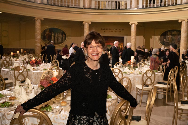 Barbara Sowinski, surrounded by many people, smiling during a dinner in the Liberal Arts Center surrounded by many people