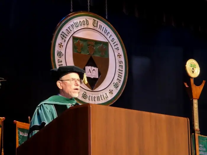 Dr. Richard Gosser standing at a podium with the Marywood University seal behind him