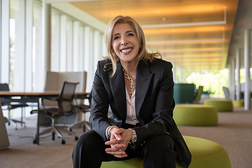 President Lori sitting down, smiling, and wearing a black suit